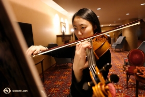 Houslistka Karen Chen a její soustředěná příprava. Umělci jako paní Chen se neustále snaží zdokonalovat své umění, nehledě na to, že letos bude mít za sebou téměř sto odehraných představení a s Shen Yun působí už jedenáctou sezonu. (fotila Annie Li)