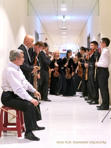 V zákulisí – členové symfonického orchestru jsou téměř připraveni vkročit do koncertní síně.