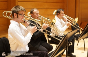 Sekce trombonistů společně trénuje před zkouškou. Zleva doprava: Alistair Crawford (první trombonista), Ivan Agarkov a Pavlo Baishev (pozounista).